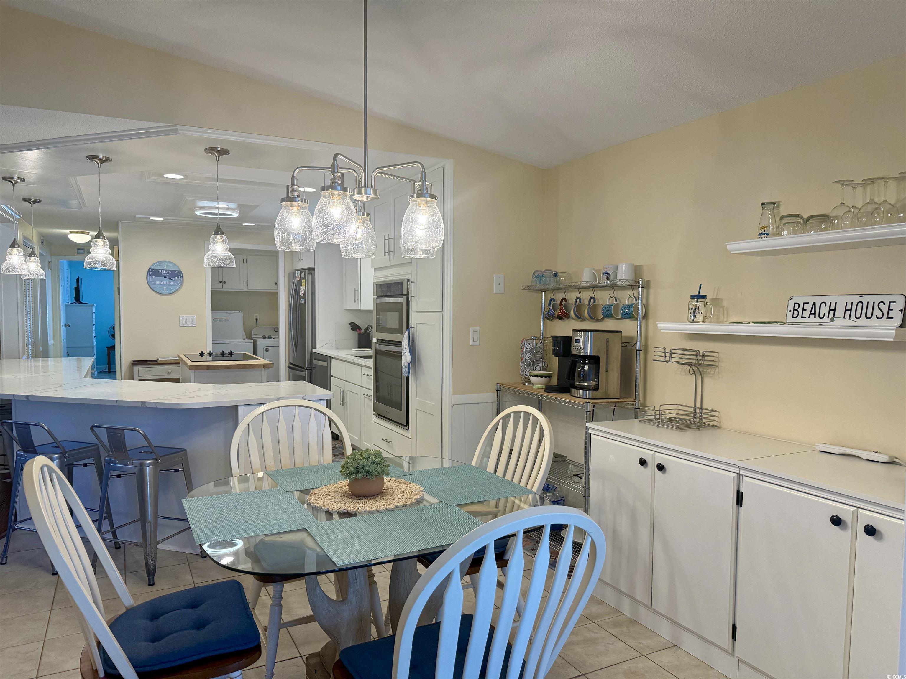 416 Oceanside Drive Surfside Beach, SC 29575 - Photo 6 of 37 Dining space featuring washer / clothes dryer, light tile patterned flooring, lofted ceiling, and a wainscoted wall
