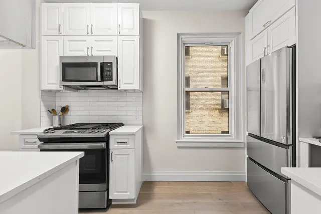 a kitchen with white cabinets and black appliances