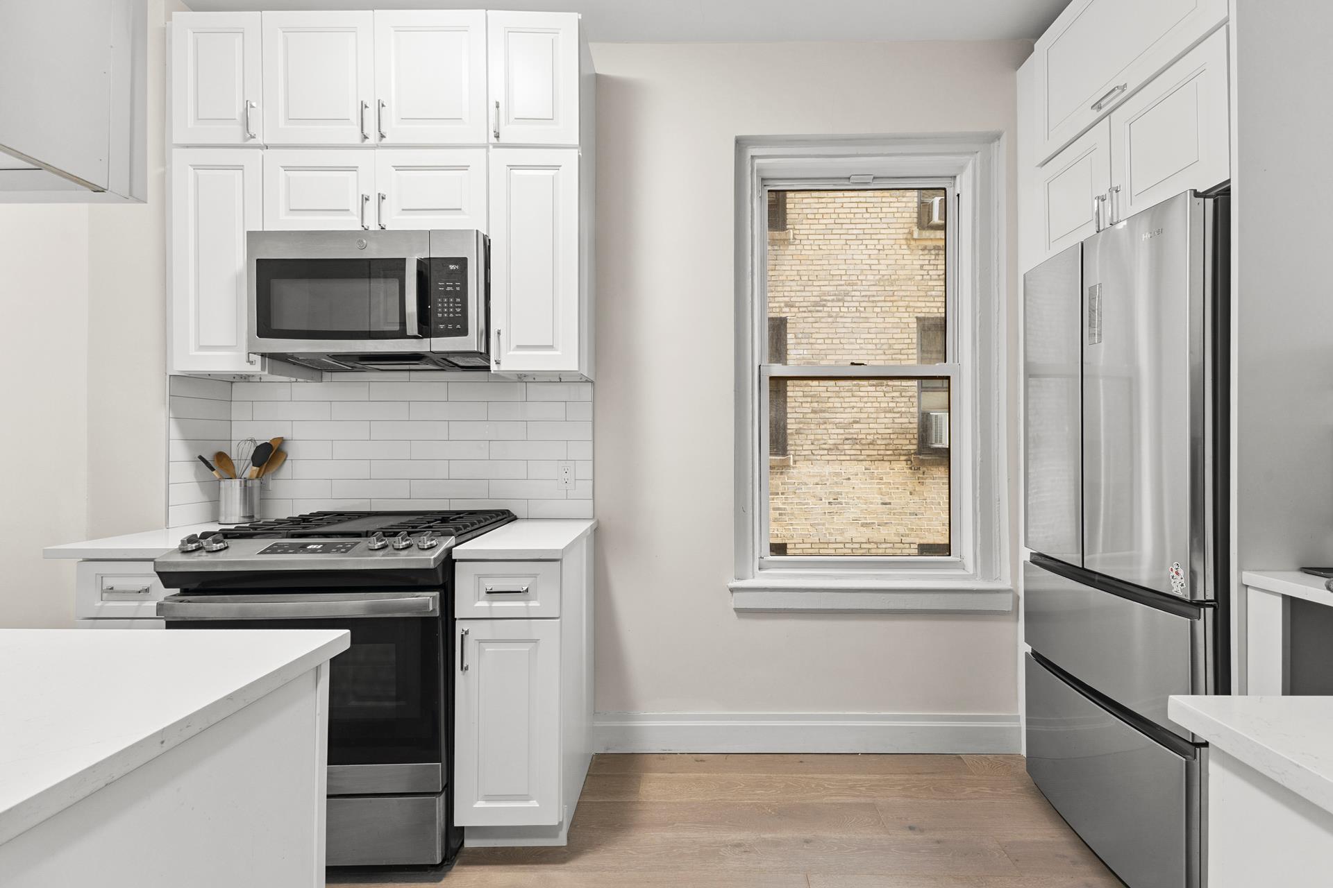 172 East 4th Street, Unit 6C Manhattan, NY 10009 - Photo 4 of 7 a kitchen with white cabinets and black appliances