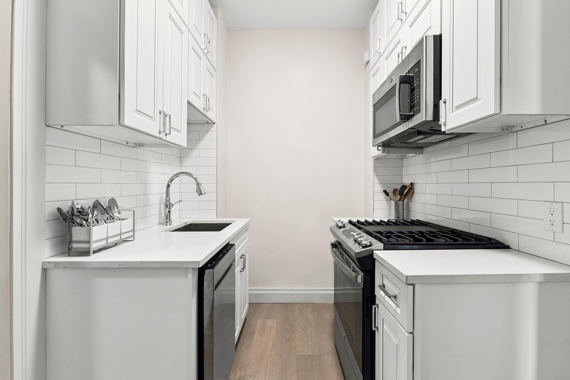 172 East 4th Street, Unit 6C Manhattan, NY 10009 - Photo 5 of 7 a kitchen with stainless steel appliances granite countertop a sink stove and cabinets