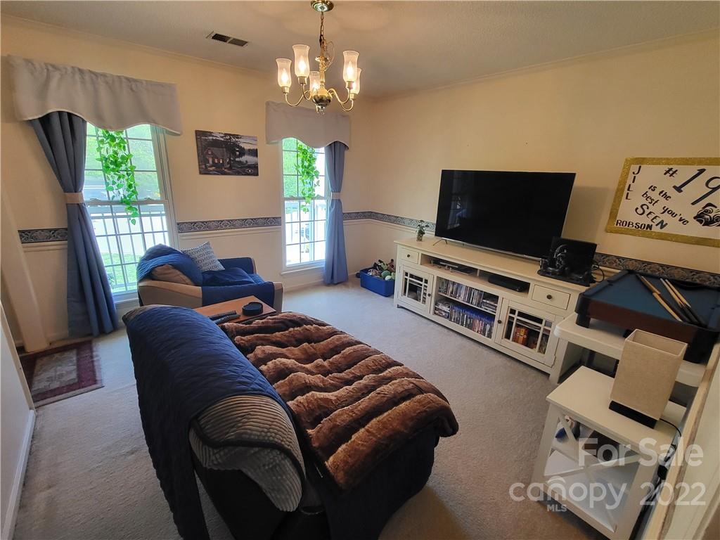 9216 Torrence Crossing Drive Huntersville, NC 28078 - Photo 6 of 34 a living room with furniture a flat screen tv and a chandelier