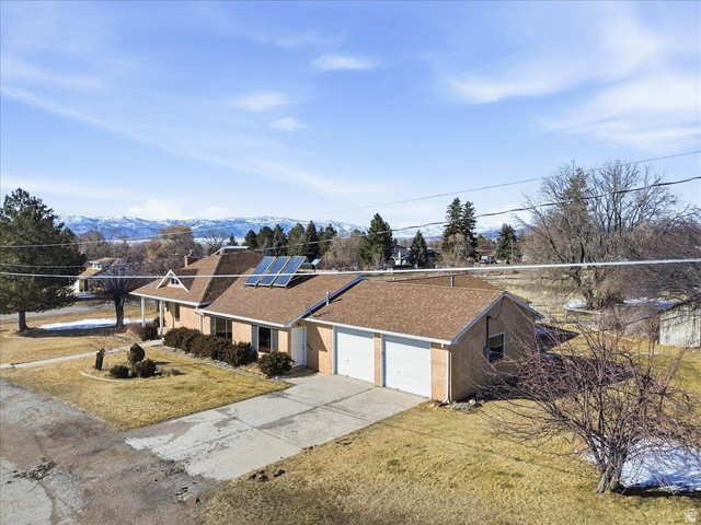 217 East 400 South Spring City, UT 84662 - Photo 56 of 71 Ranch-style home with roof mounted solar panels, concrete driveway, a front lawn, a shingled roof, and a garage