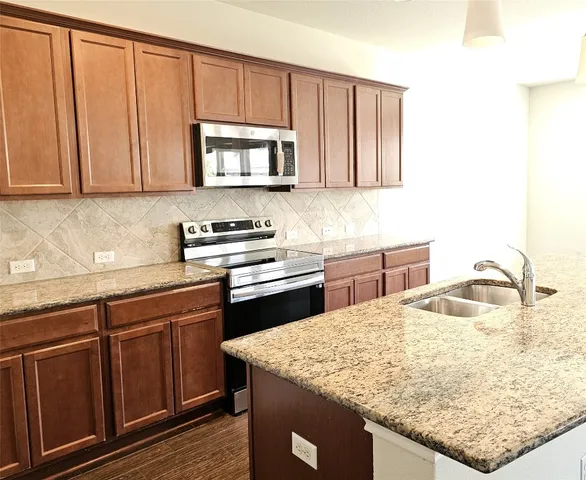 a kitchen with stainless steel appliances granite countertop wooden cabinets a stove and dishwasher