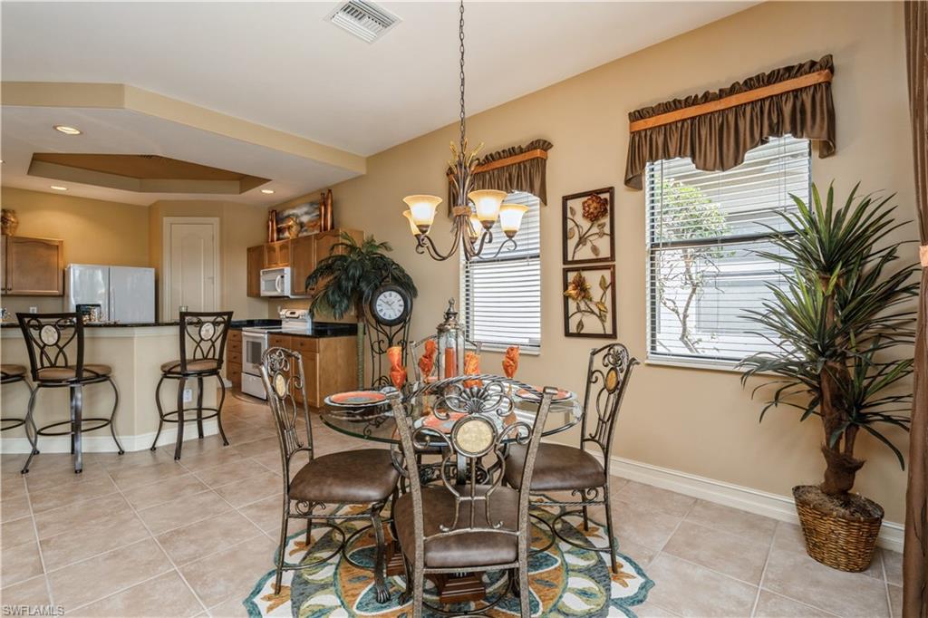 1411 Serrano Circle Naples, FL 34105 - Photo 19 of 50 Dining room with a raised ceiling, light tile patterned floors, and a notable chandelier