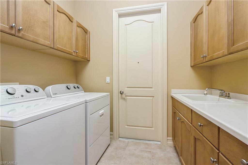 1411 Serrano Circle Naples, FL 34105 - Photo 33 of 50 Washroom featuring sink, light tile patterned floors, cabinets, and independent washer and dryer