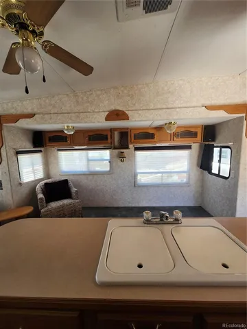 a living room with stainless steel appliances furniture large windows and a kitchen view