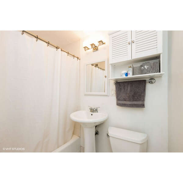 2930 North Sheridan Road, Unit 1008 Chicago, IL 60657 - Photo 7 of 12 a bathroom with a sink a mirror and a shower