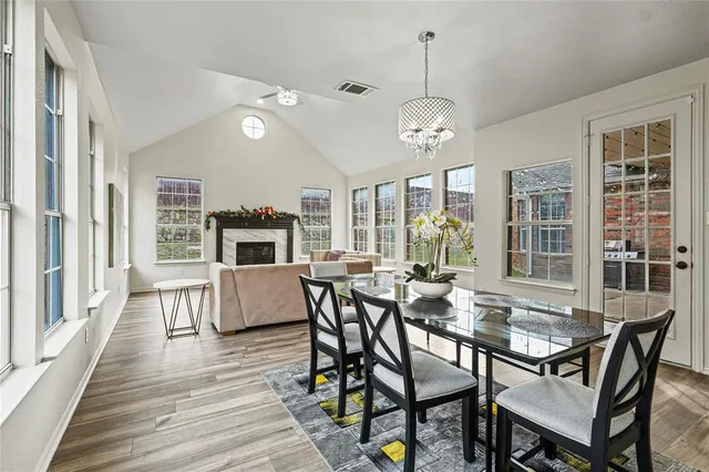 a dining room with wooden floor a chandelier a wooden table and chairs