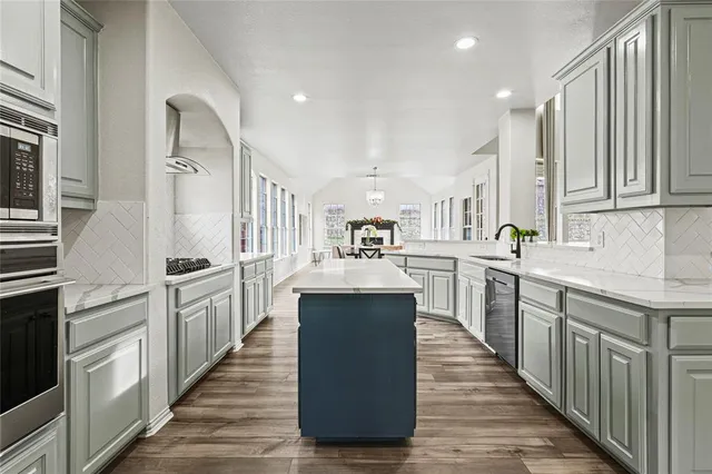 a kitchen with stainless steel appliances granite countertop a refrigerator a stove and a sink