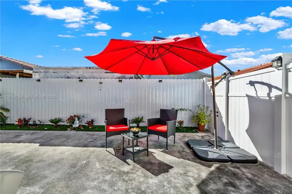 a view of a patio with table and chairs under an umbrella