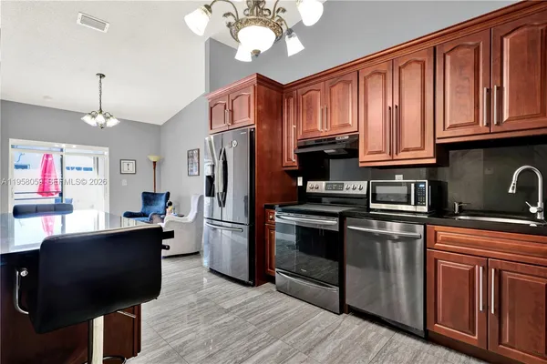 a kitchen with stainless steel appliances granite countertop a refrigerator a stove top oven a sink dishwasher and wooden cabinets