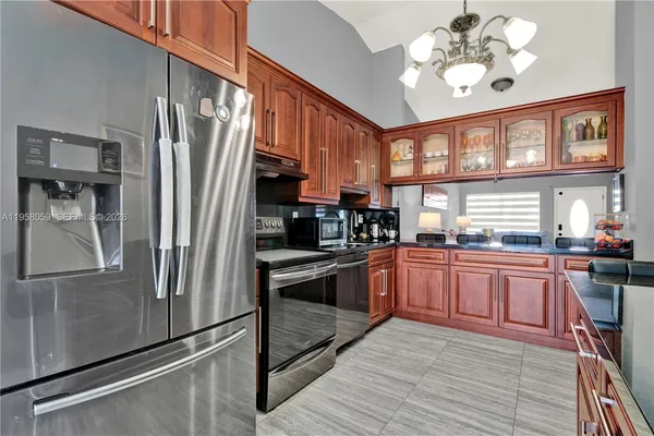 a kitchen with stainless steel appliances granite countertop a refrigerator a stove and a sink with wooden floor