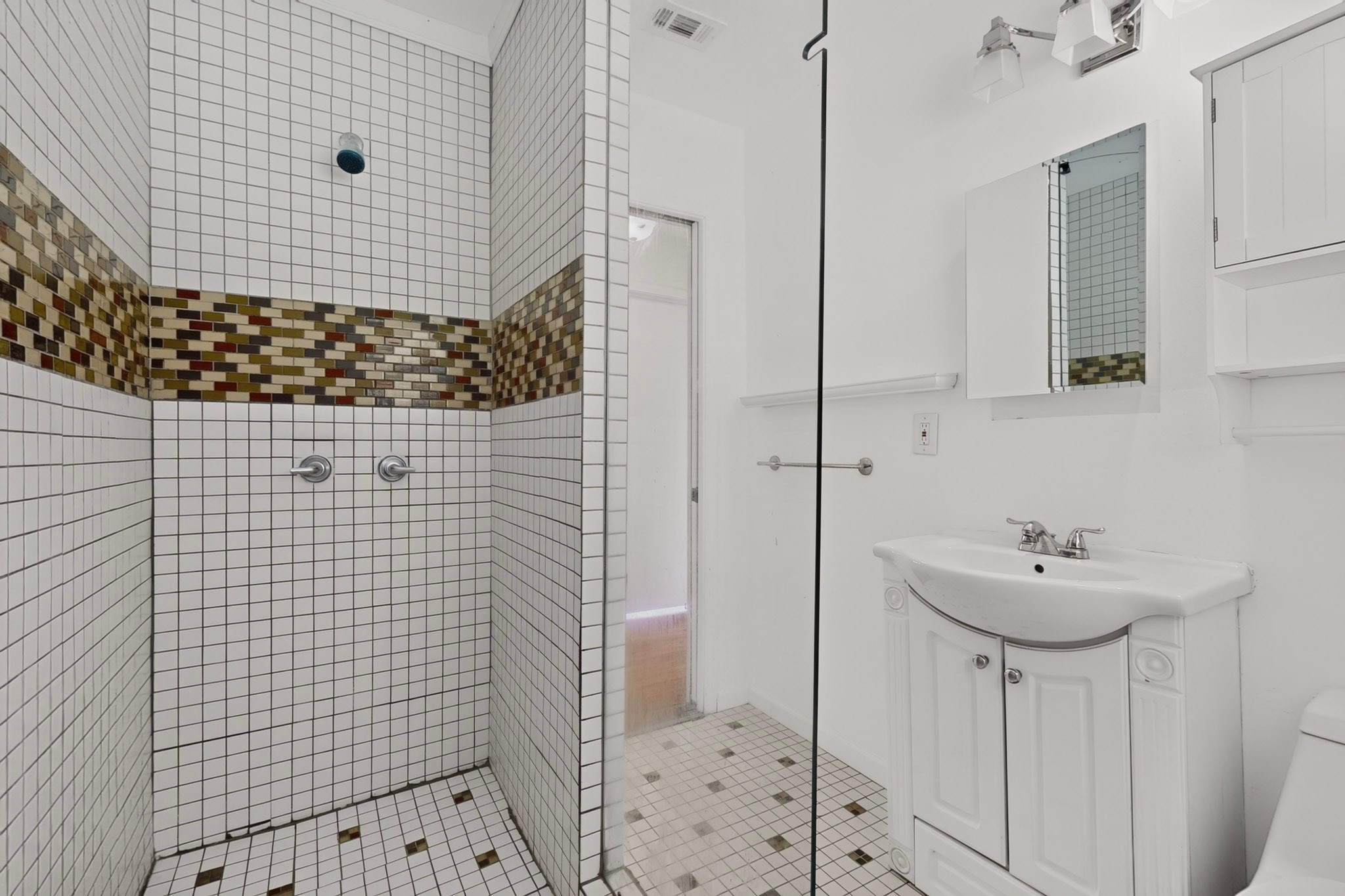4711 Alf Avenue Austin, TX 78721 - Photo 22 of 34 Tiled shower with decorative accent bands complements a clean white vanity