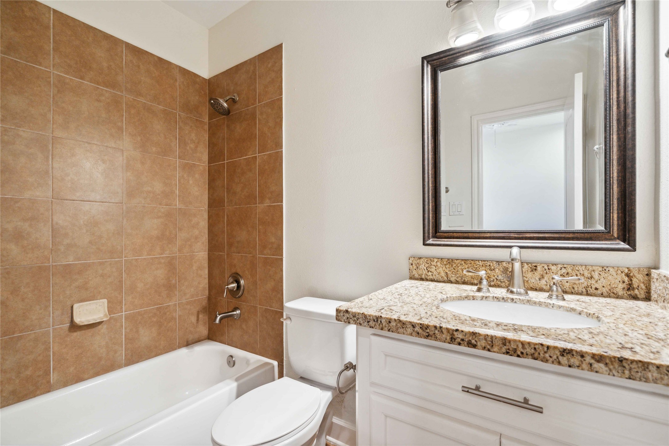 5402 Jonathan Lane Houston, TX 77011 - Photo 14 of 19 a bathroom with a granite countertop sink a mirror and a bathtub