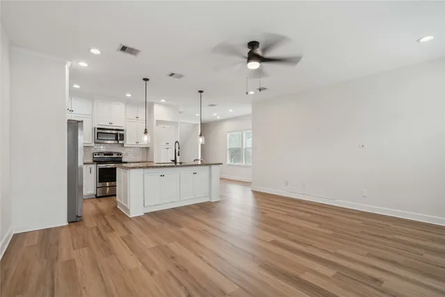 a large kitchen with stainless steel appliances granite countertop a lot of cabinets and wooden floor
