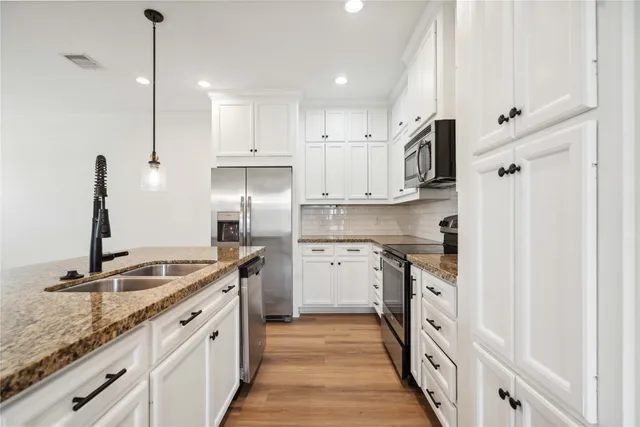 a kitchen with granite countertop kitchen island a sink stainless steel appliances and cabinets
