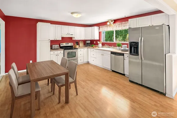 a kitchen with stainless steel appliances a table chairs refrigerator and a window