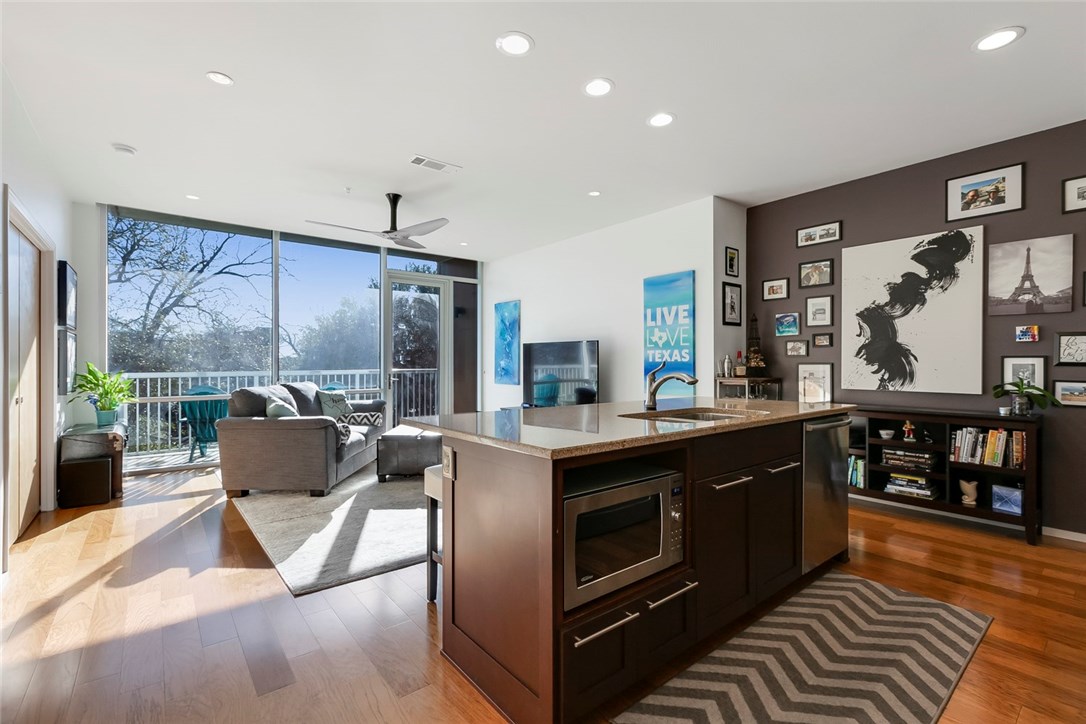 a kitchen with stainless steel appliances granite countertop a stove and a view of living room