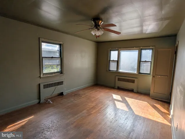 a view of an empty room with a window and wooden floor