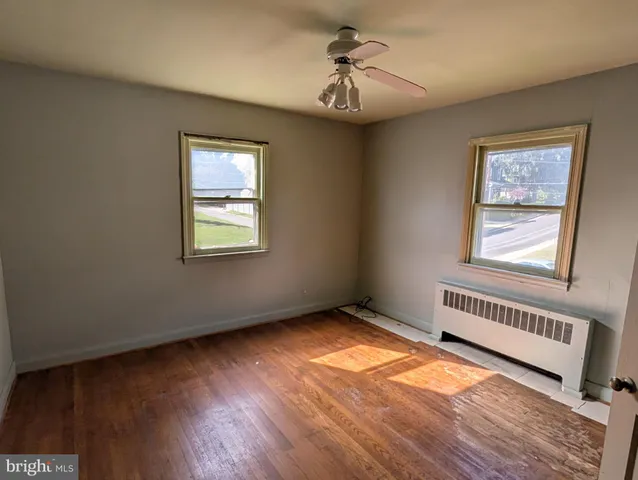 a view of an empty room with a window and wooden floor