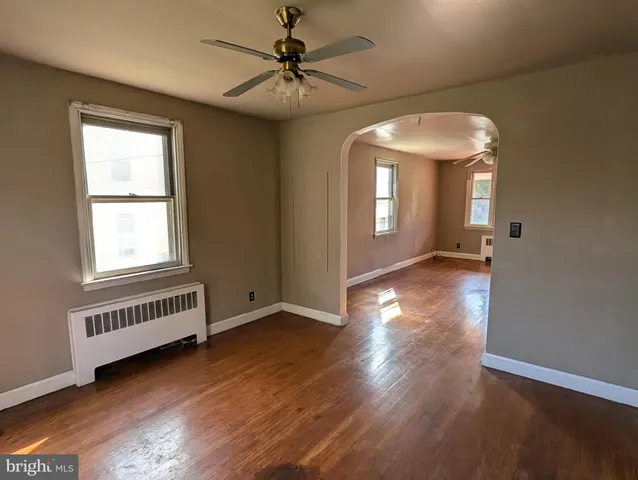 an empty room with wooden floor chandelier and windows