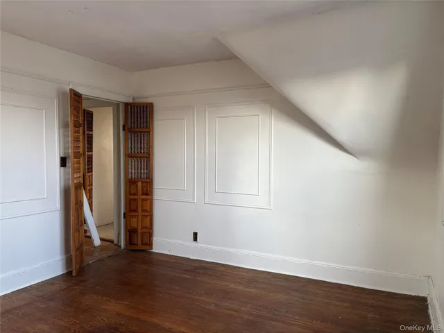 a view of an empty room with wooden floor and closet