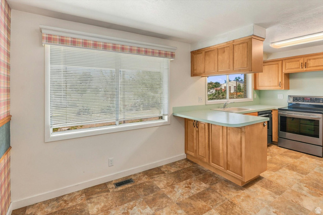 15295 North 5400th Street West Riverside, UT 84334 - Photo 8 of 54 Kitchen featuring wood cabinetry, stainless steel range, light green countertops, and patterned floor tile