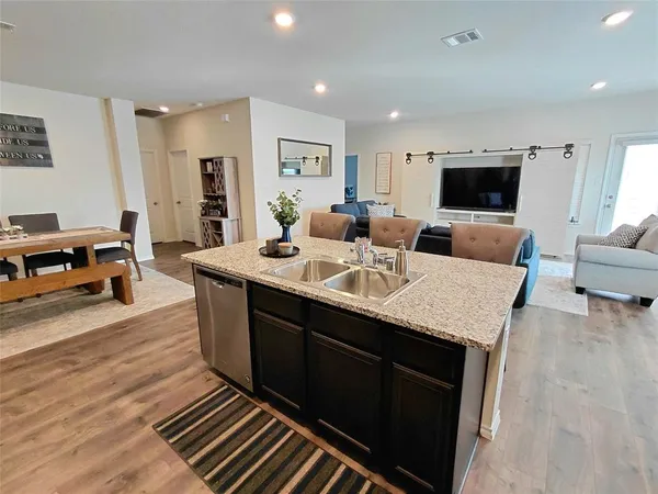a large kitchen with stainless steel appliances kitchen island granite countertop a sink and a refrigerator