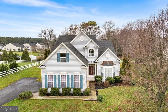 a view of a white house next to a yard with big trees