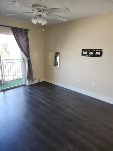 an empty room with wooden floor chandelier fan and windows