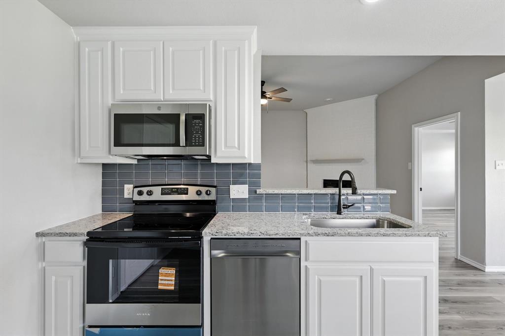 621 Torero Trail Oak Point, TX 75068 - Photo 11 of 34 a kitchen with granite countertop a stove microwave and sink