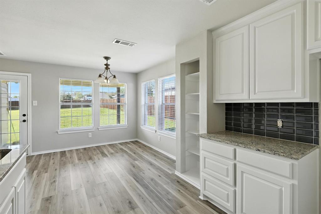 621 Torero Trail Oak Point, TX 75068 - Photo 17 of 34 a kitchen with granite countertop white cabinets and wooden floor