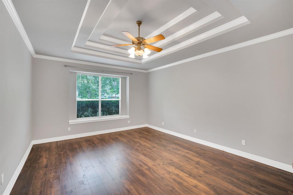 1907 Timber Ridge Court Cedar Hill, TX 75104 - Photo 13 of 30 Spacious room featuring a tiered tray ceiling with a central ceiling fan, wood-finish flooring, and light gray walls