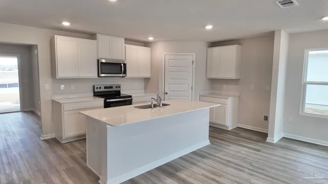 a large white kitchen with wooden floor and a sink