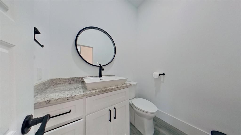 3248 North Cardinal Road Azle, TX 76020 - Photo 27 of 29 Powder room featuring a white floating vessel sink, matte black faucet, and a round framed mirror