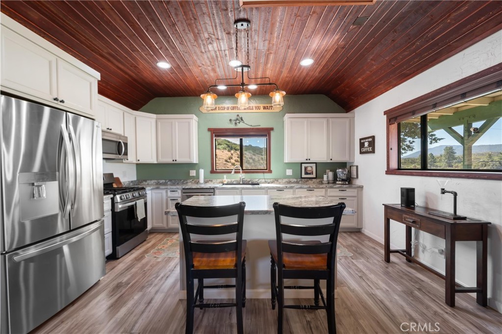 60861 Burnt Valley Road Anza, CA 92539 - Photo 13 of 66 a kitchen with stainless steel appliances granite countertop a stove refrigerator a dining table and chairs with wooden floor