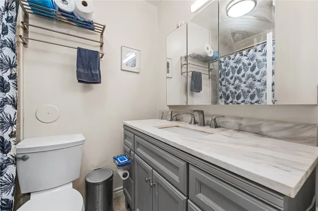 a bathroom with a granite countertop toilet sink and mirror