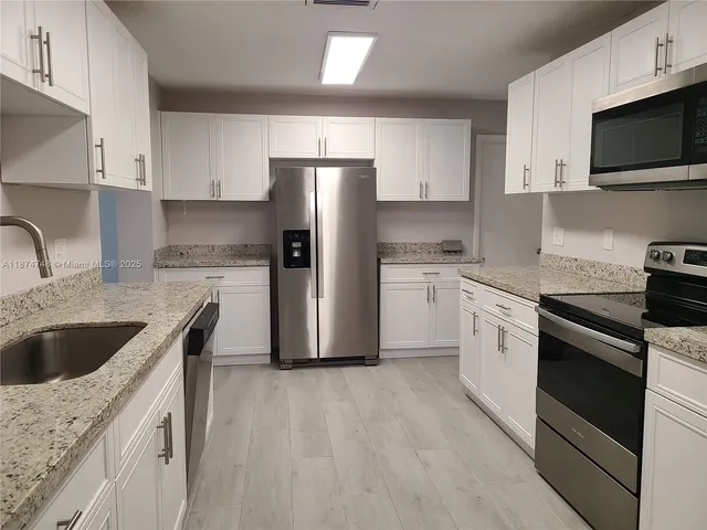 a kitchen with stainless steel appliances granite countertop a sink a stove a refrigerator and cabinets