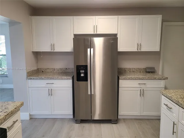 a kitchen with granite countertop cabinets and refrigerator