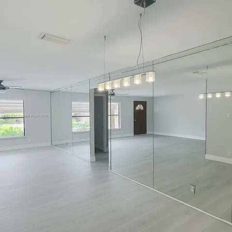 a view of an empty room with window and chandelier fan