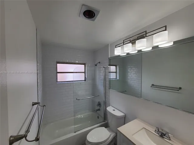 a bathroom with a granite countertop toilet sink and mirror