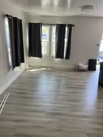 a view of a livingroom with wooden floor and kitchen space