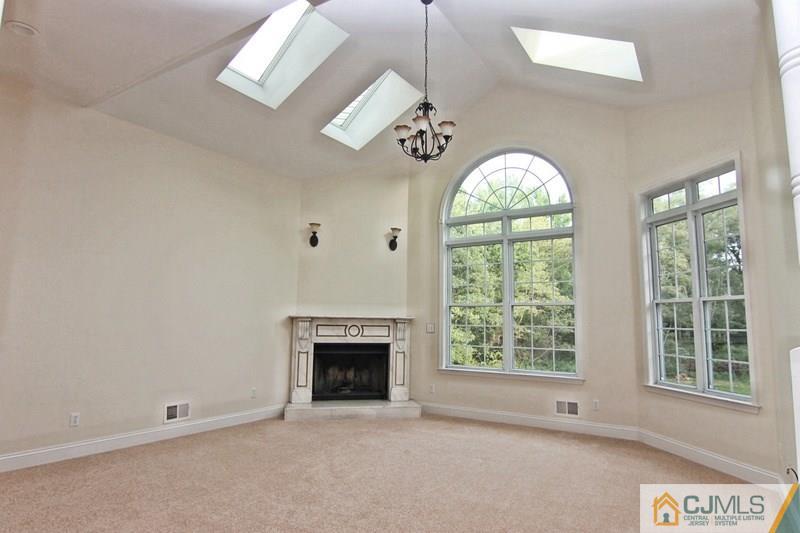 238 Fresh Ponds Road Monroe Township, NJ 08831 - Photo 8 of 17 an empty room with windows fireplace and chandelier