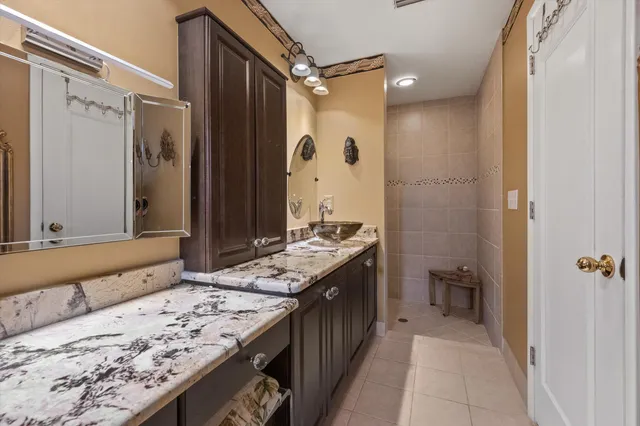 a bathroom with a granite countertop sink a mirror and a shower