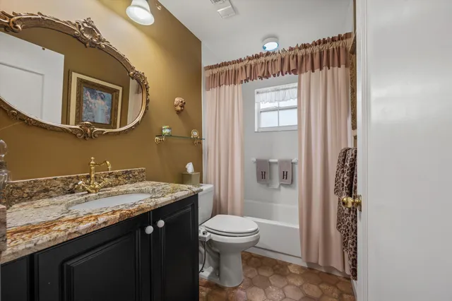 a bathroom with a granite countertop sink toilet a mirror and shower