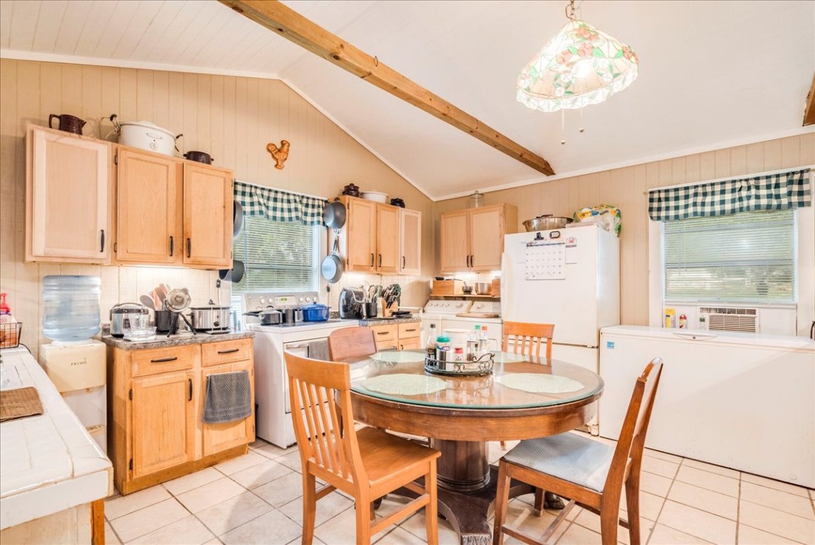 2411 Rohde Road Kyle, TX 78640 - Photo 12 of 40 Kitchen with light brown cabinets, pendant lighting, light tile patterned flooring, tile countertops, and wooden walls