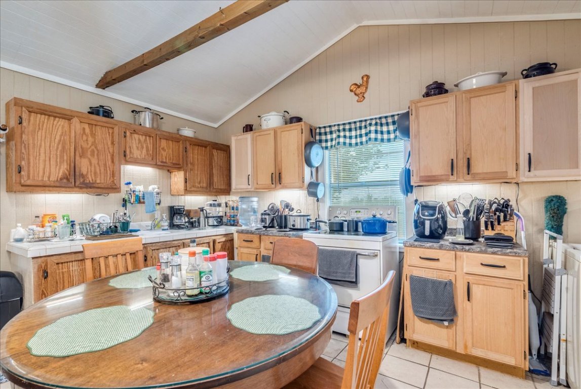 2411 Rohde Road Kyle, TX 78640 - Photo 13 of 40 Kitchen featuring tasteful backsplash, light tile patterned floors, light brown cabinets, and white range with electric stovetop