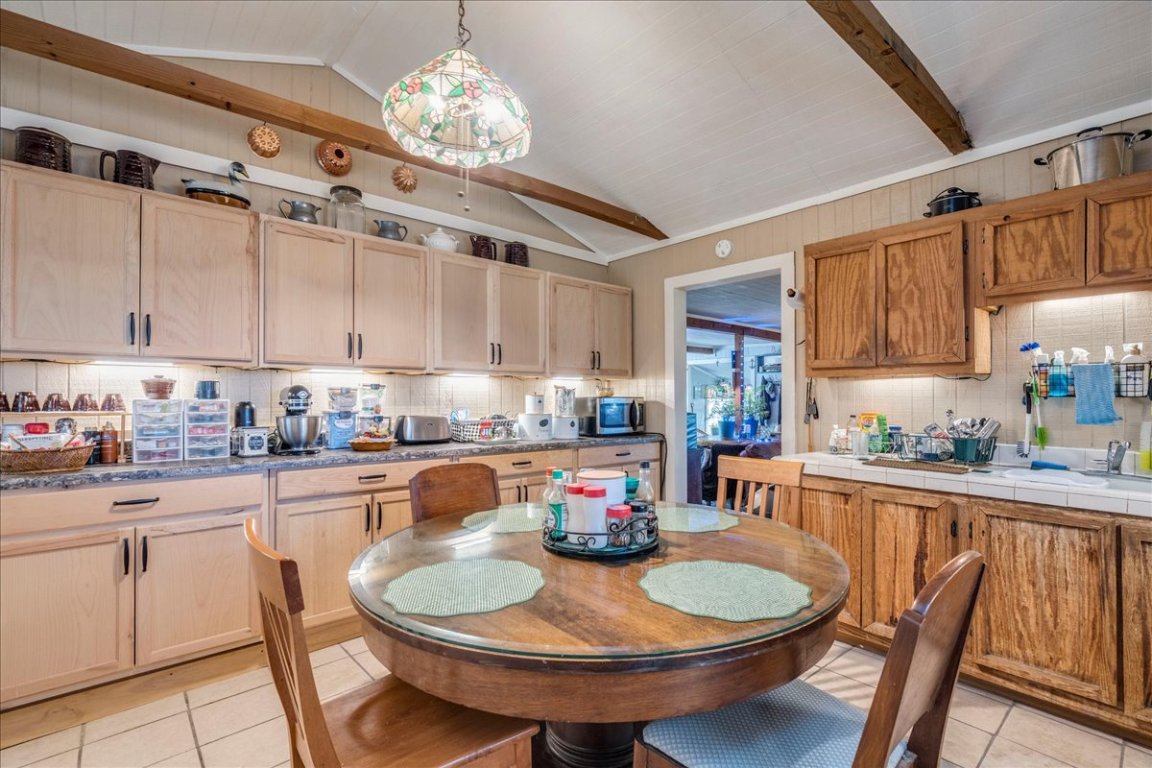 2411 Rohde Road Kyle, TX 78640 - Photo 14 of 40 Kitchen with decorative backsplash, light tile patterned floors, decorative light fixtures, tile counters, and stainless steel microwave