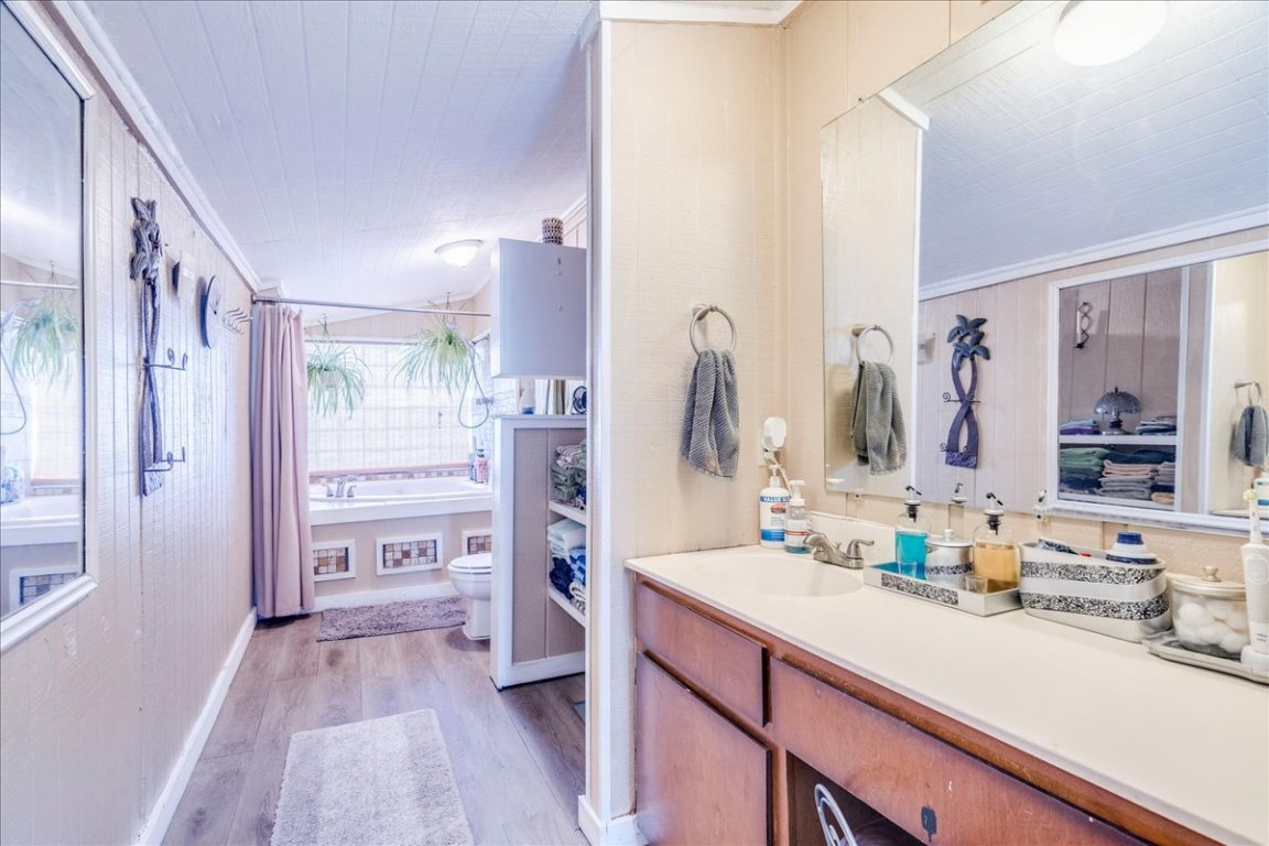 2411 Rohde Road Kyle, TX 78640 - Photo 19 of 40 Full bathroom with light wood-style floors, vanity, crown molding, shower / bath combination with curtain, and wood walls