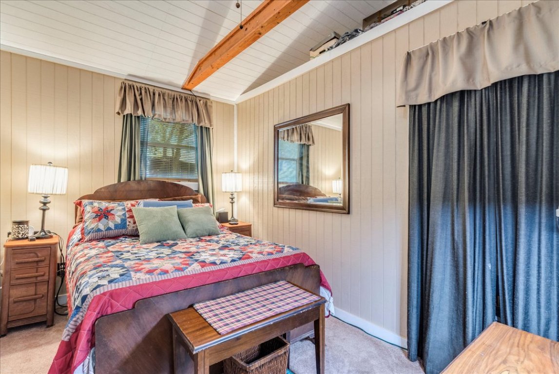 2411 Rohde Road Kyle, TX 78640 - Photo 22 of 40 Bedroom featuring beamed ceiling, light carpet, and wood walls